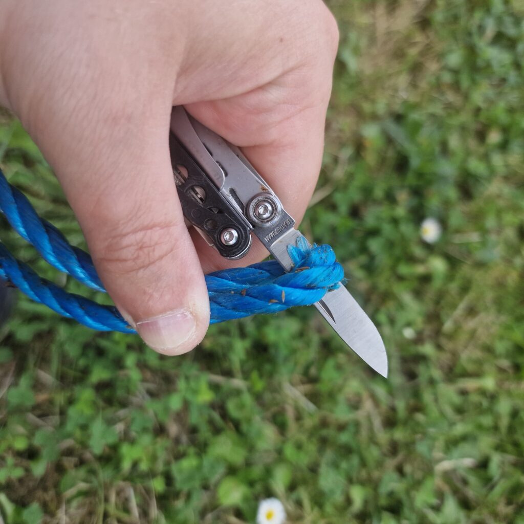 Picture showing an Every Day Carry multi tool cutting through some blue polypropylene rope. 
