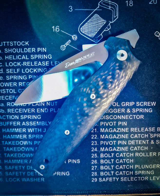 Photo of the Viper DAN2 knife on an AR-15 cleaning mat with blue lens flare showing the knife partially opened.