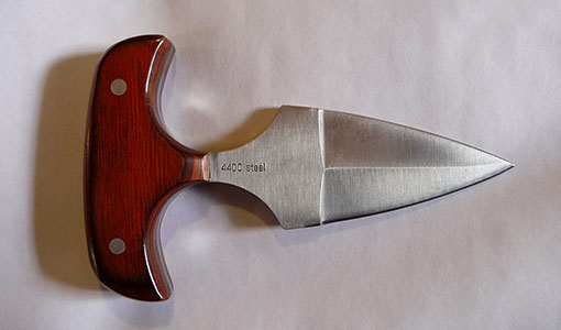 A pushdagger, with red handle shown on a white background. Banned under UK Knife laws.