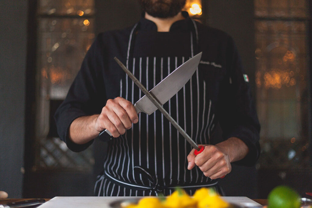 How to sharpen a knife with a ceramic rod - photo showing a chef using a sharpening steel to polish his knife edge. 
