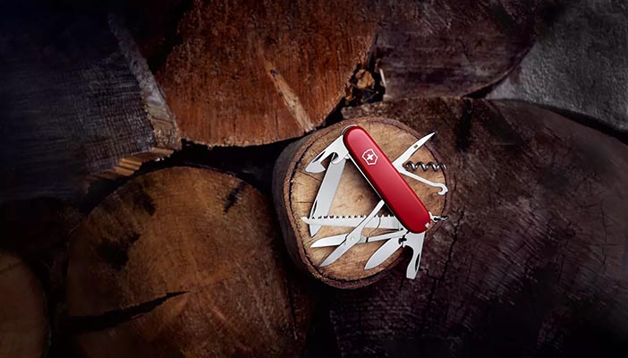 Swiss Army Knife by Victorinox placed, almost glowing on a bed of tree trunk sections with all tools open. It looks ready to jump into action at at moment.